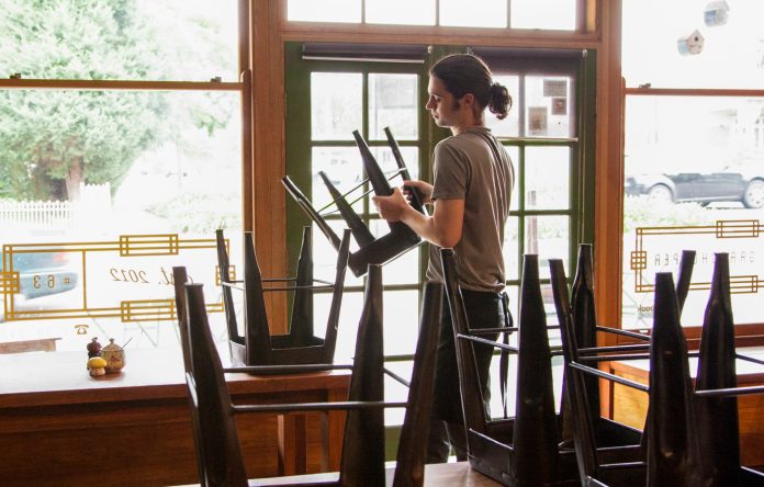 Waiter packing up cafe or restaurant chairs