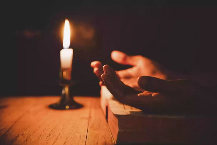 close-up-man-s-hand-is-praying-in-the-church-with-lit-candle